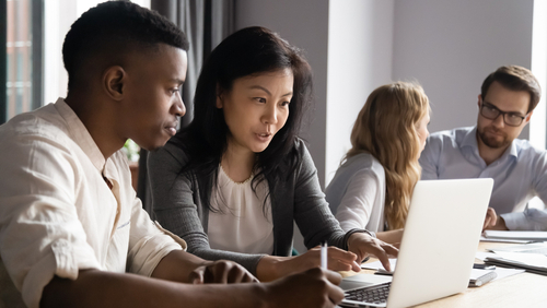Diverse team members viewing laptop screen together